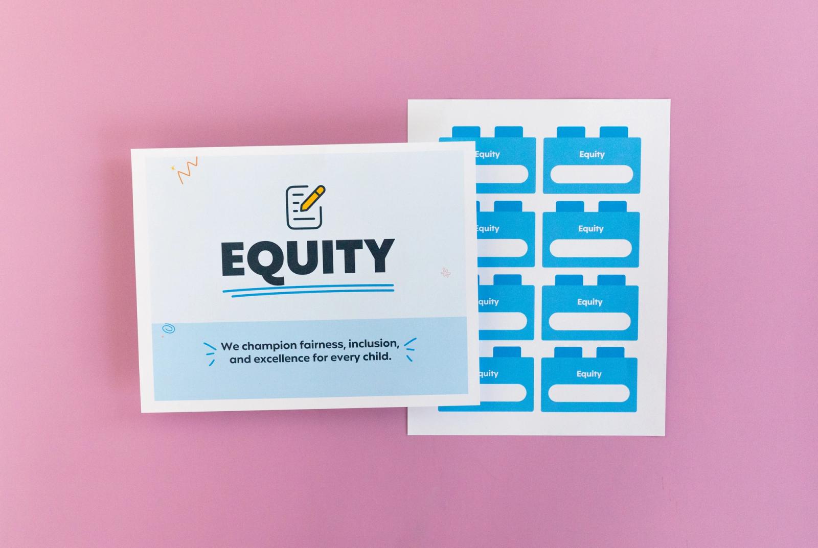 Sheet of paper that says "equity" and another with small squares on it lay on a pink background.