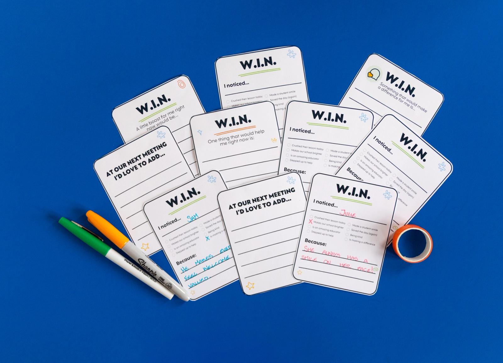 Several notecards lay on a blue background. Markers are scattered around them.