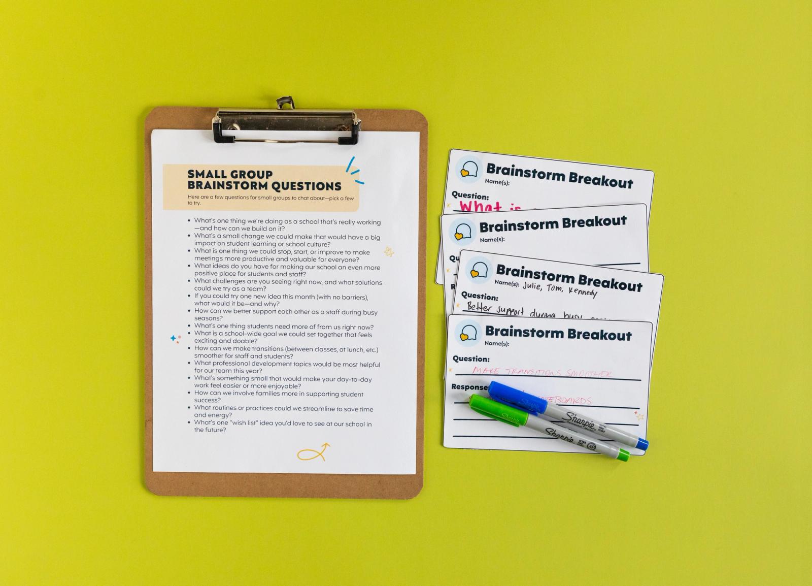 A piece of paper on a clipboard with notecards and pens beside it sit on a bright green background.