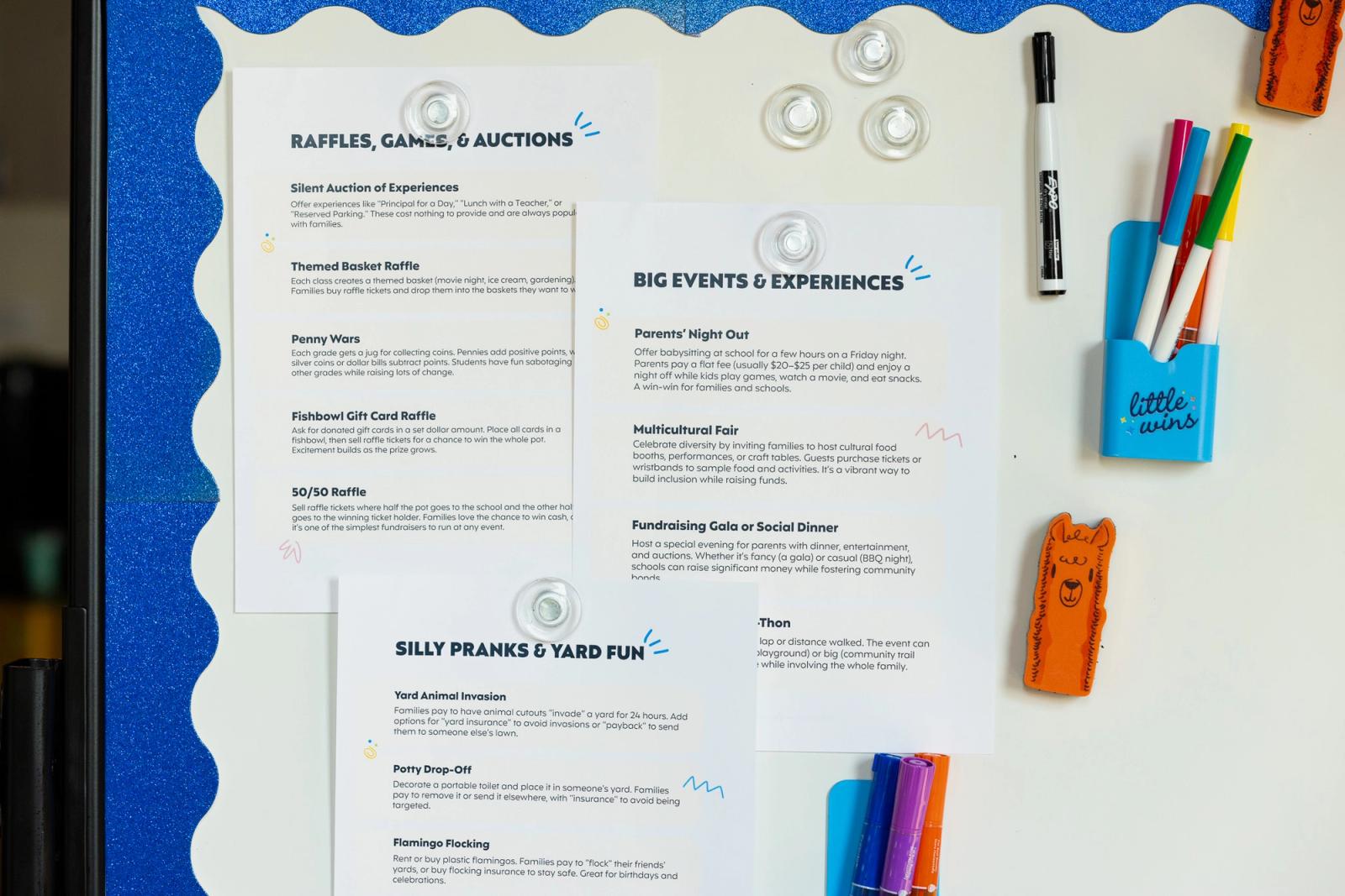 Three sheets of paper with lists of ideas are on a white bulletin board. A blue boarder and markers are around them.
