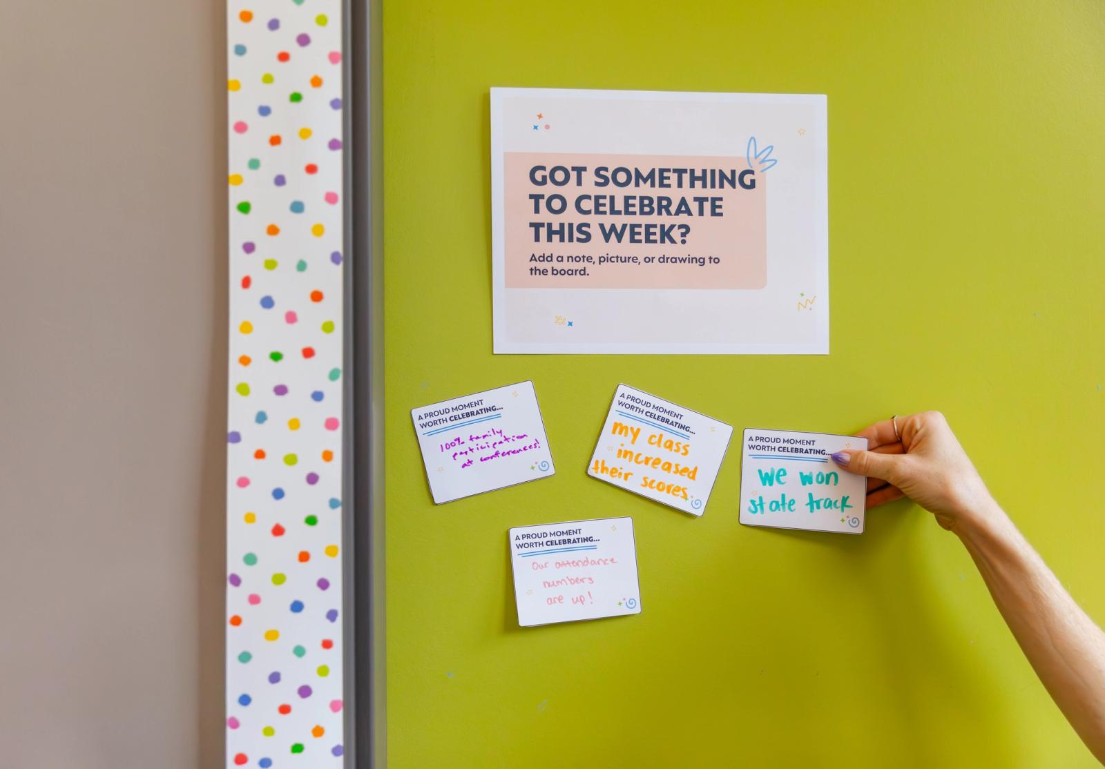 A poster hangs on a bright green bulletin board. A hand reaches in from the right and places a handwritten note underneath the poster.