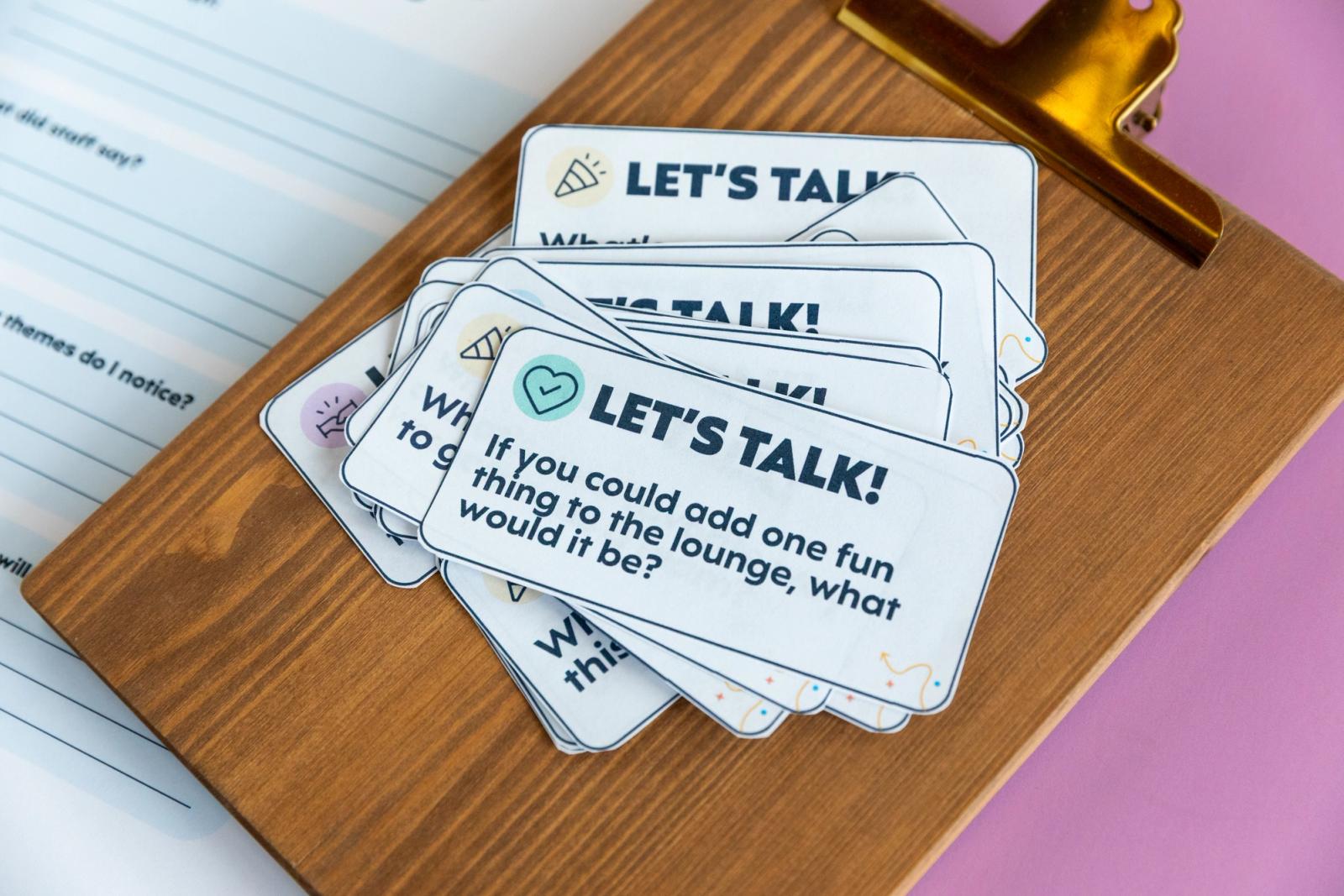 Small pieces of paper with "let's talk" printed on them lay on top of a clipboard.