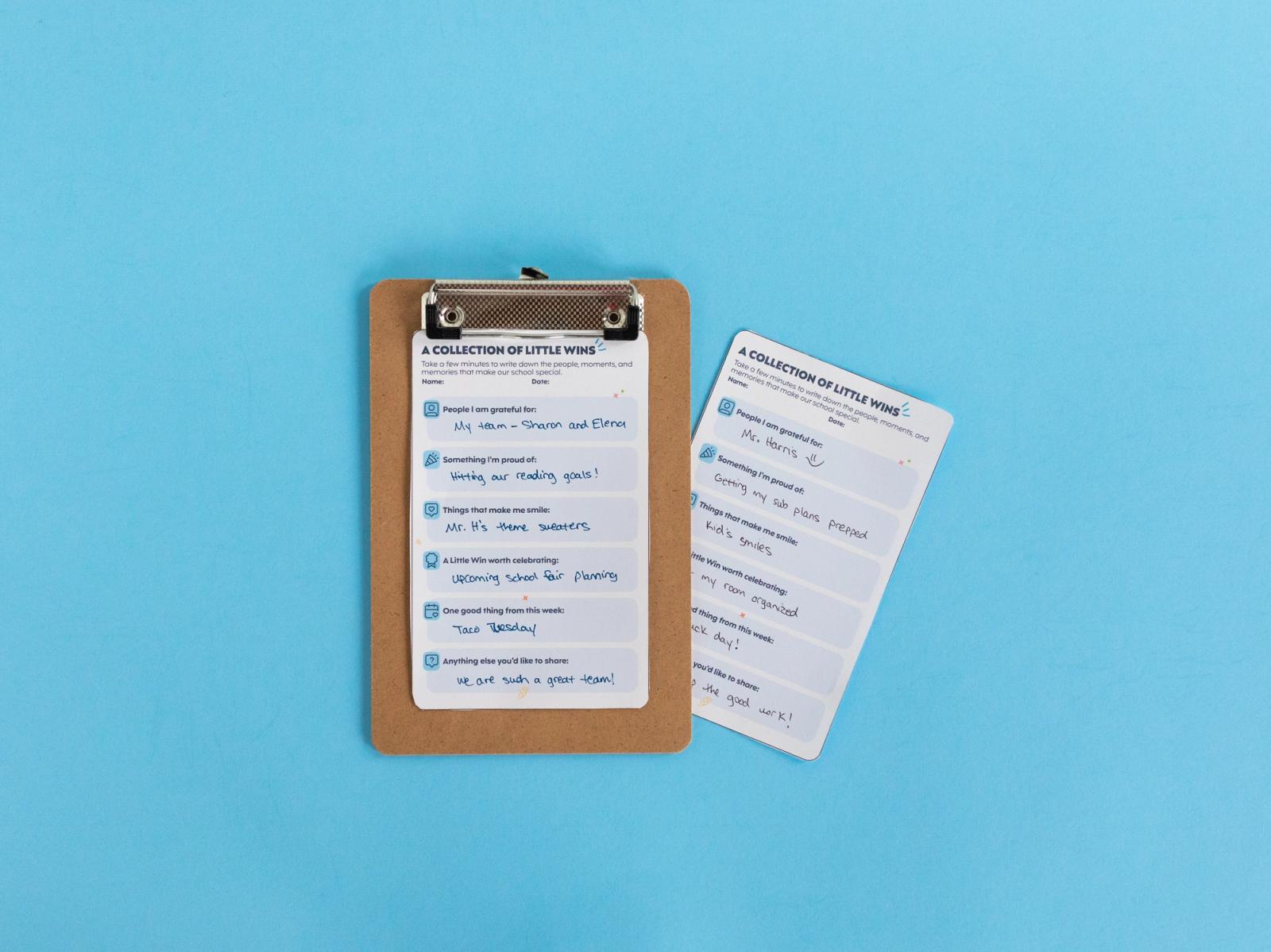 A small notecard and a clipboard with another notecard lay on a light blue background.