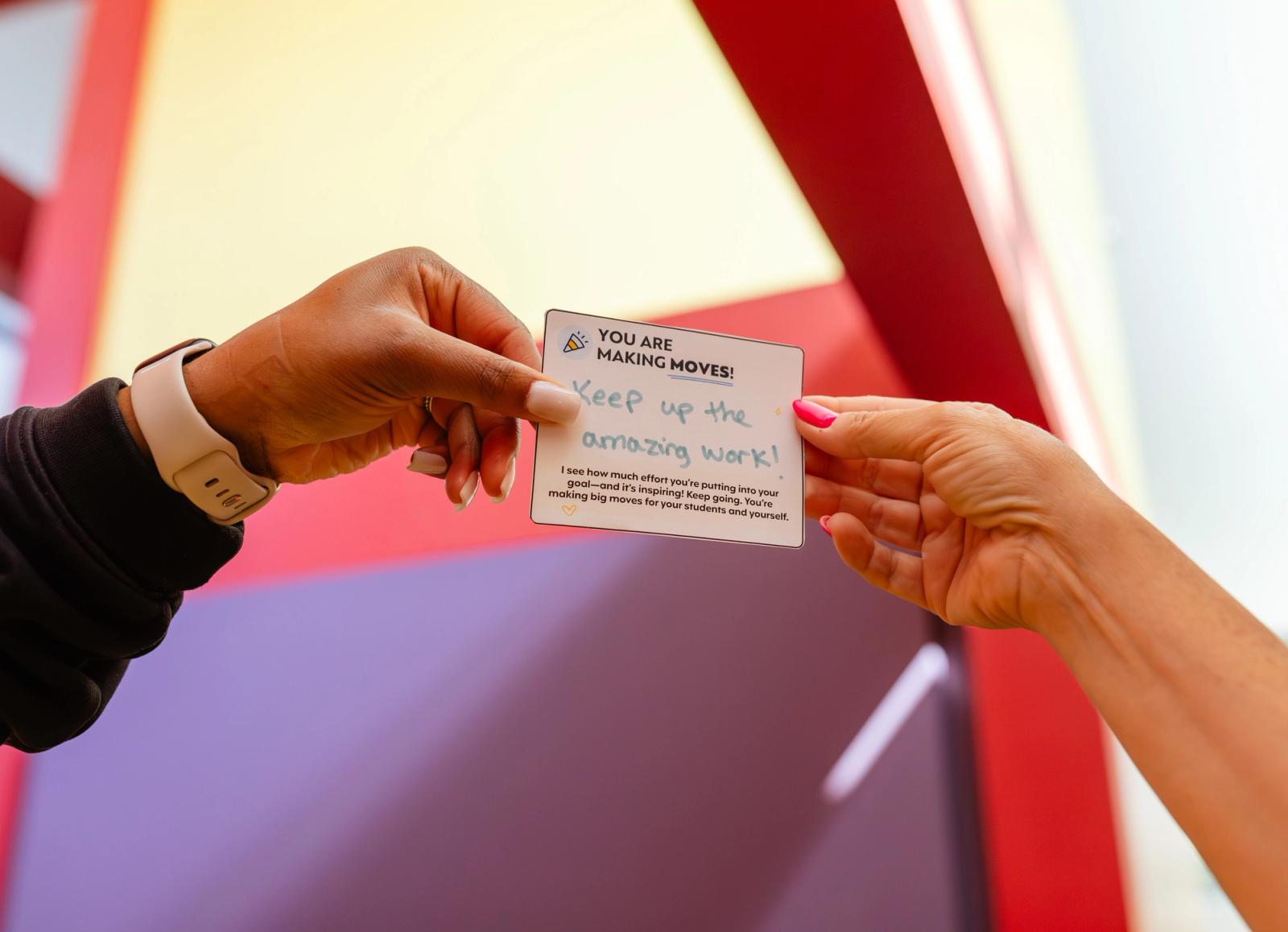 One hand reaches in to hand a hand-written note to another hand.