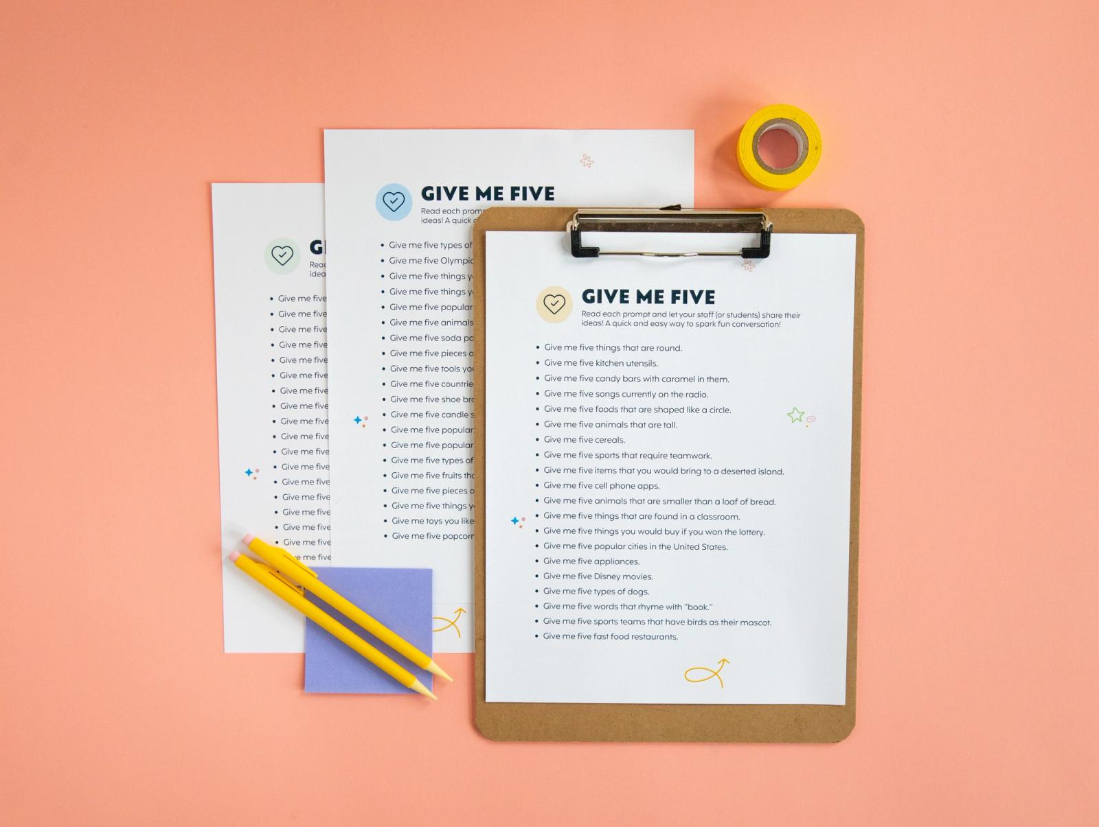 Sheets of paper that say "give me five" and a clipboard, pencils, and roll of tape lay on a peach background.