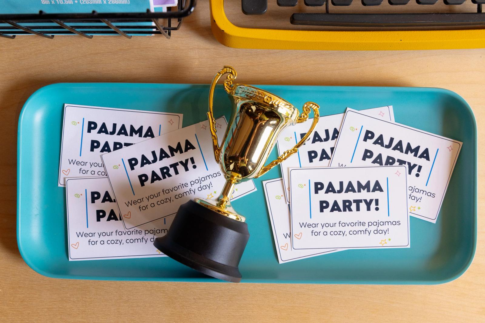 A small trophy and prize cards lay in a blue tray on a desk.