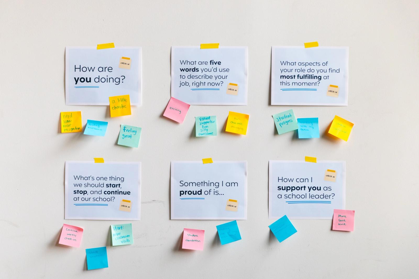 Six posters are taped on a white wall. Colorful sticky notes are around them.