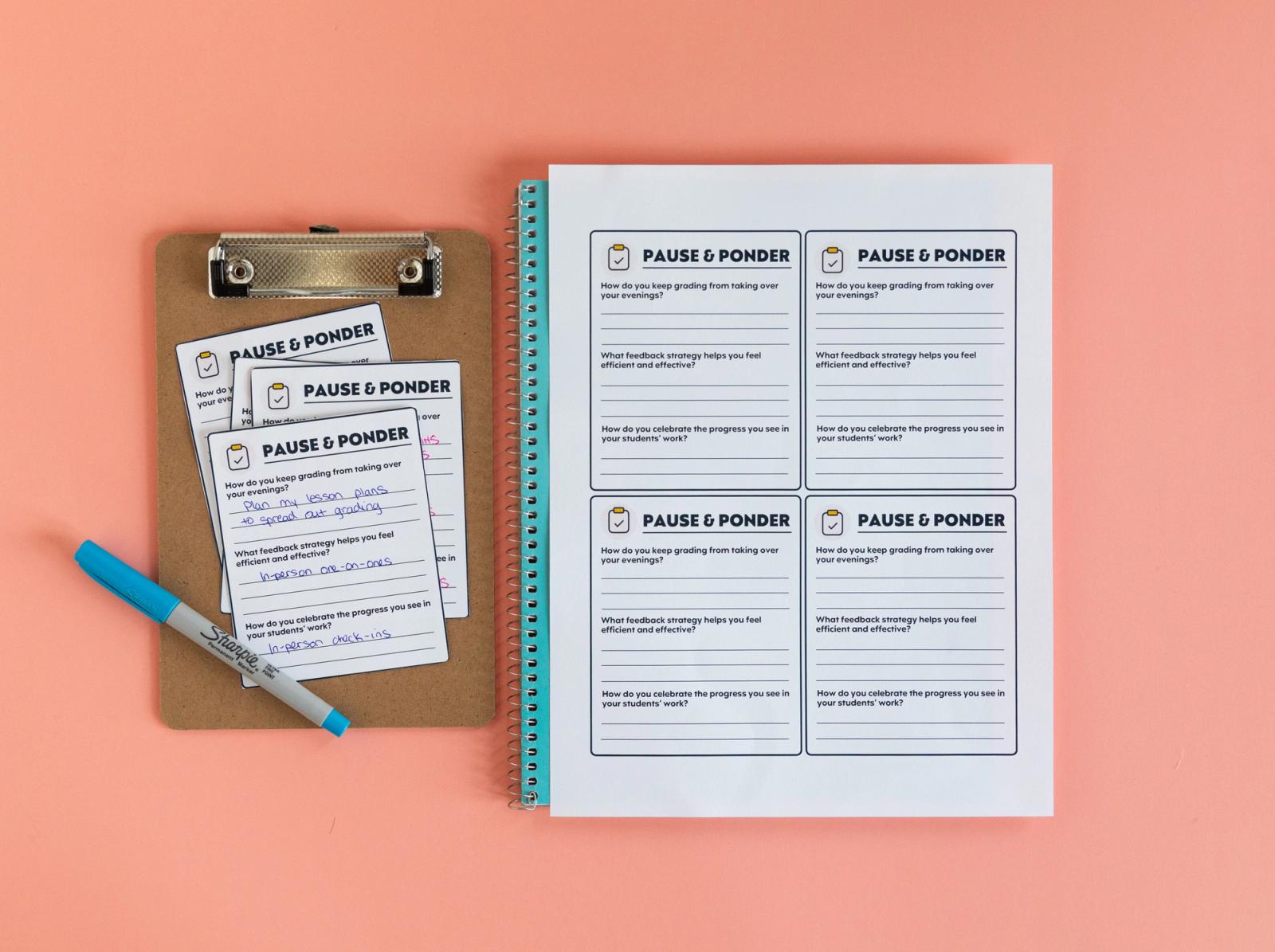 A small clipboard with notecards and a blue pen on it lays on a salmon background. Beside it is a blue notebook with a piece of paper on it.