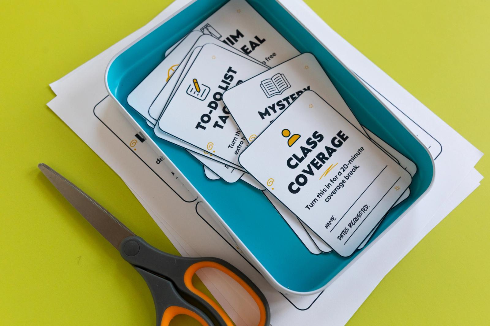 A stack of small paper coupons lay in a blue container with a pair of scissors on the side. On a bright green background.
