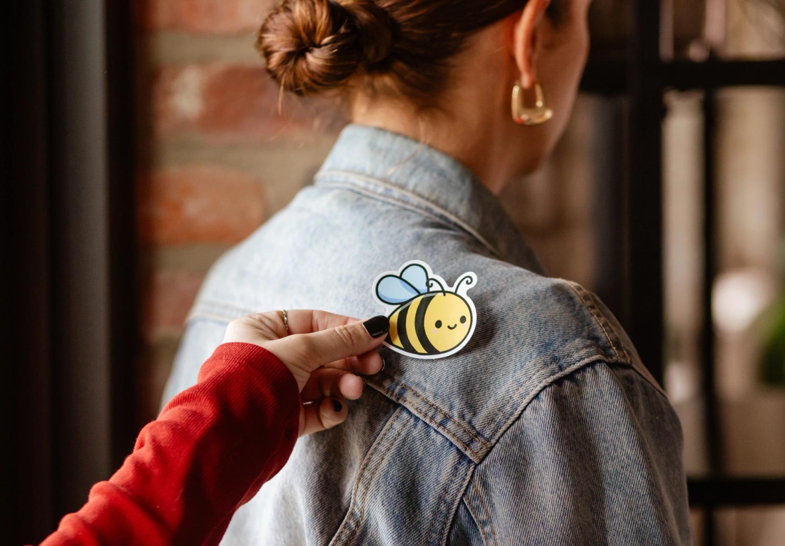 A hand places a sticker on someone's shoulder.