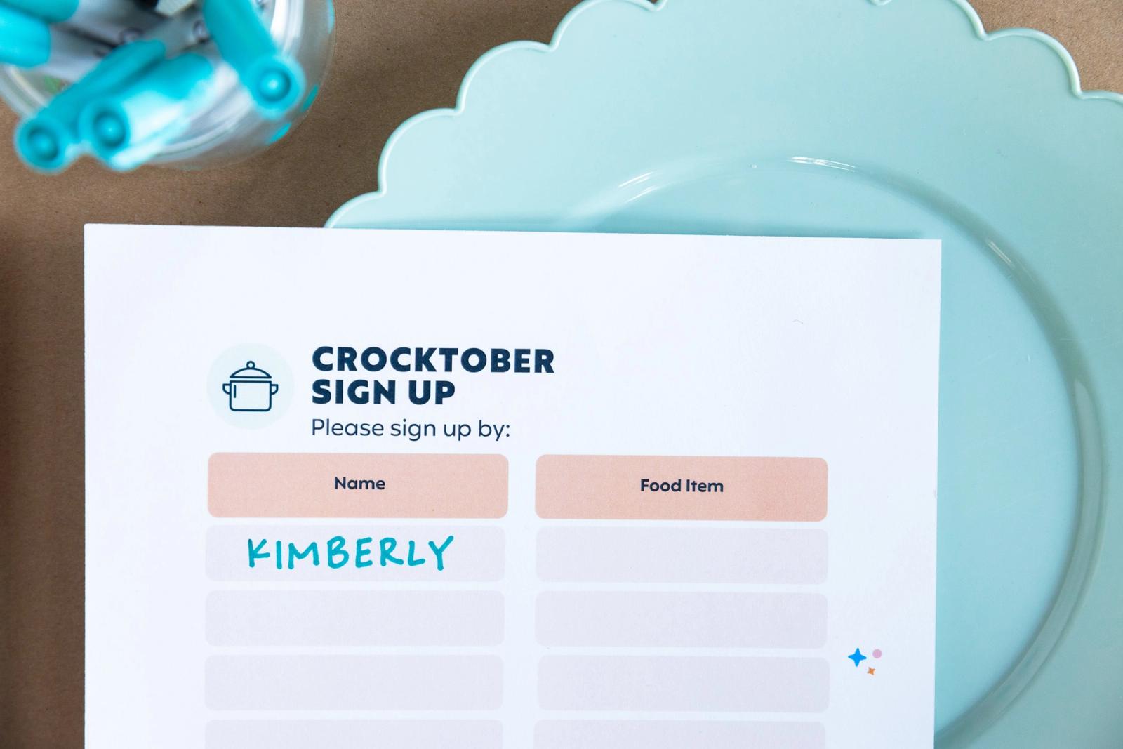 A poster that says "crocktober sign up" on it lays on top of a light blue plate.