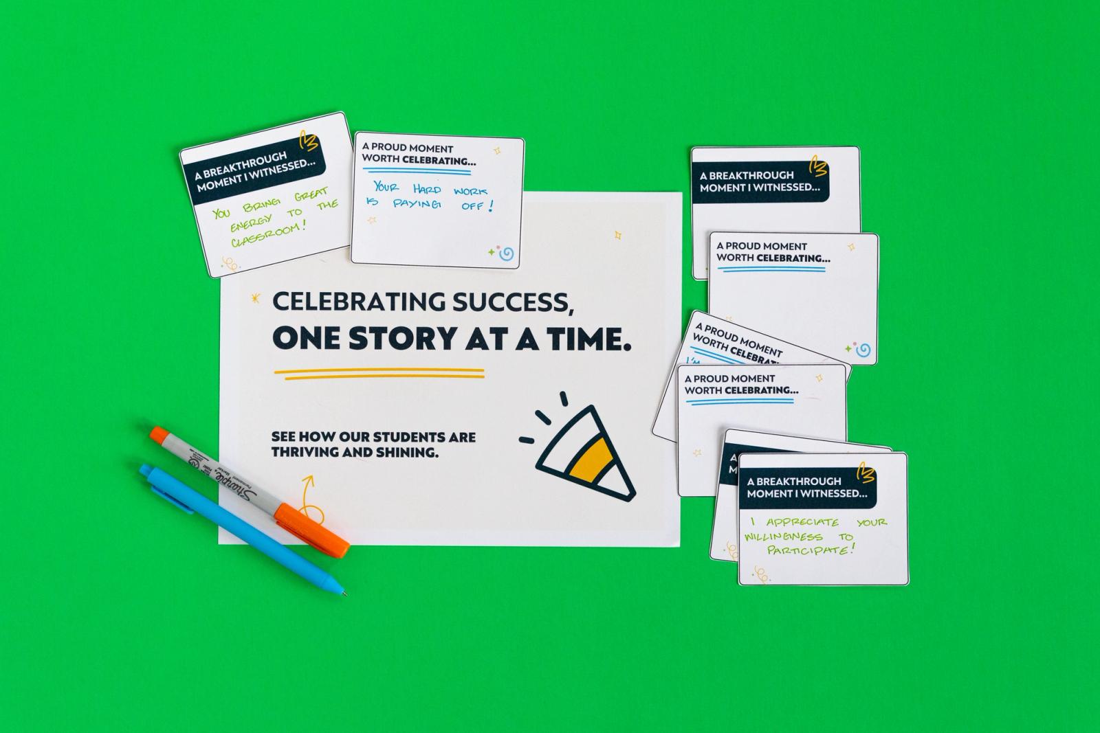 One large piece of paper and several smaller pieces of paper with typing on them lay on a green background with two pens on the side.