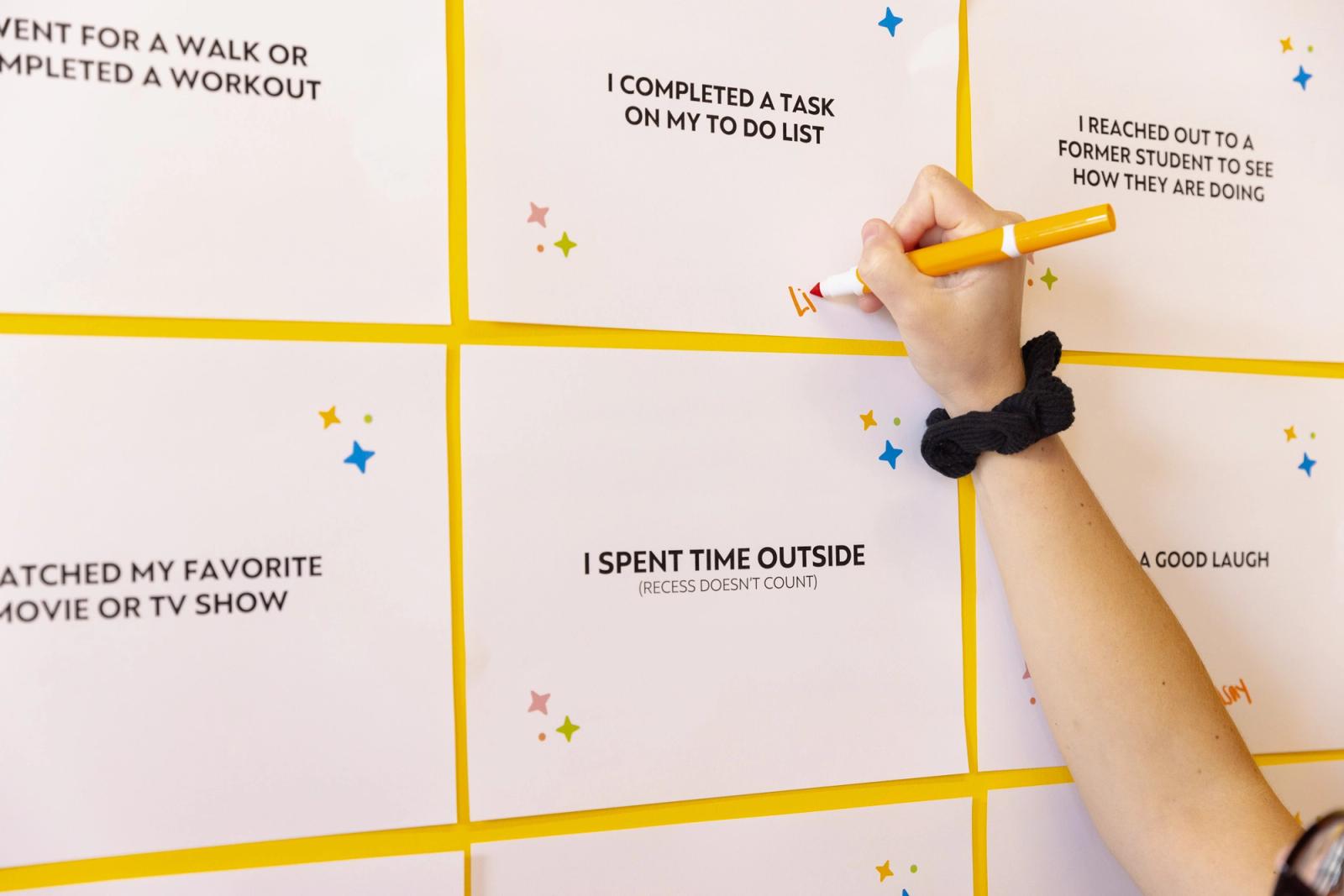A hand writes on a piece of paper on the wall. 