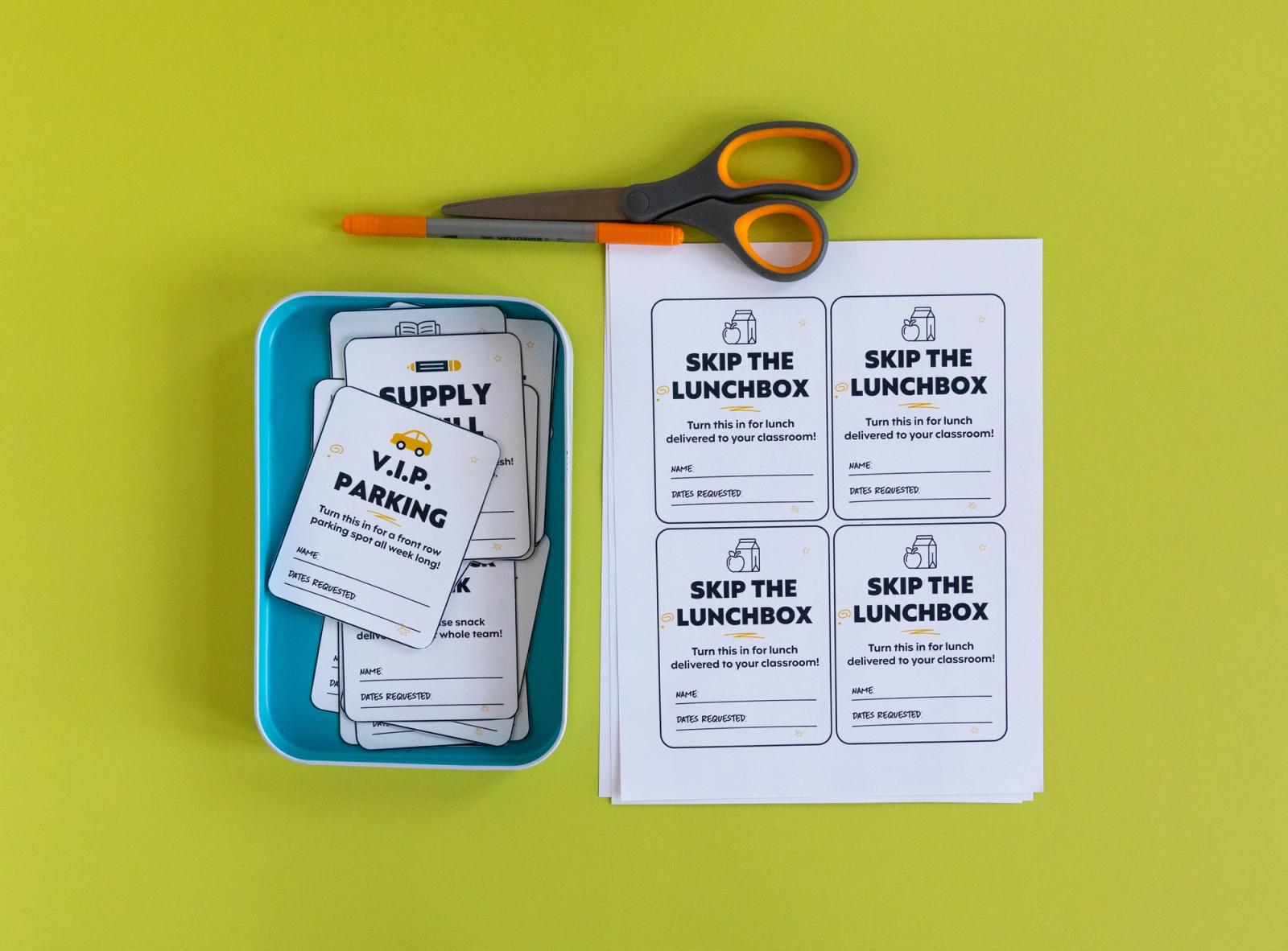 Sheets of paper and a basket of small notecards on a bright green background. A pen and pair of scissors are above the paper.
