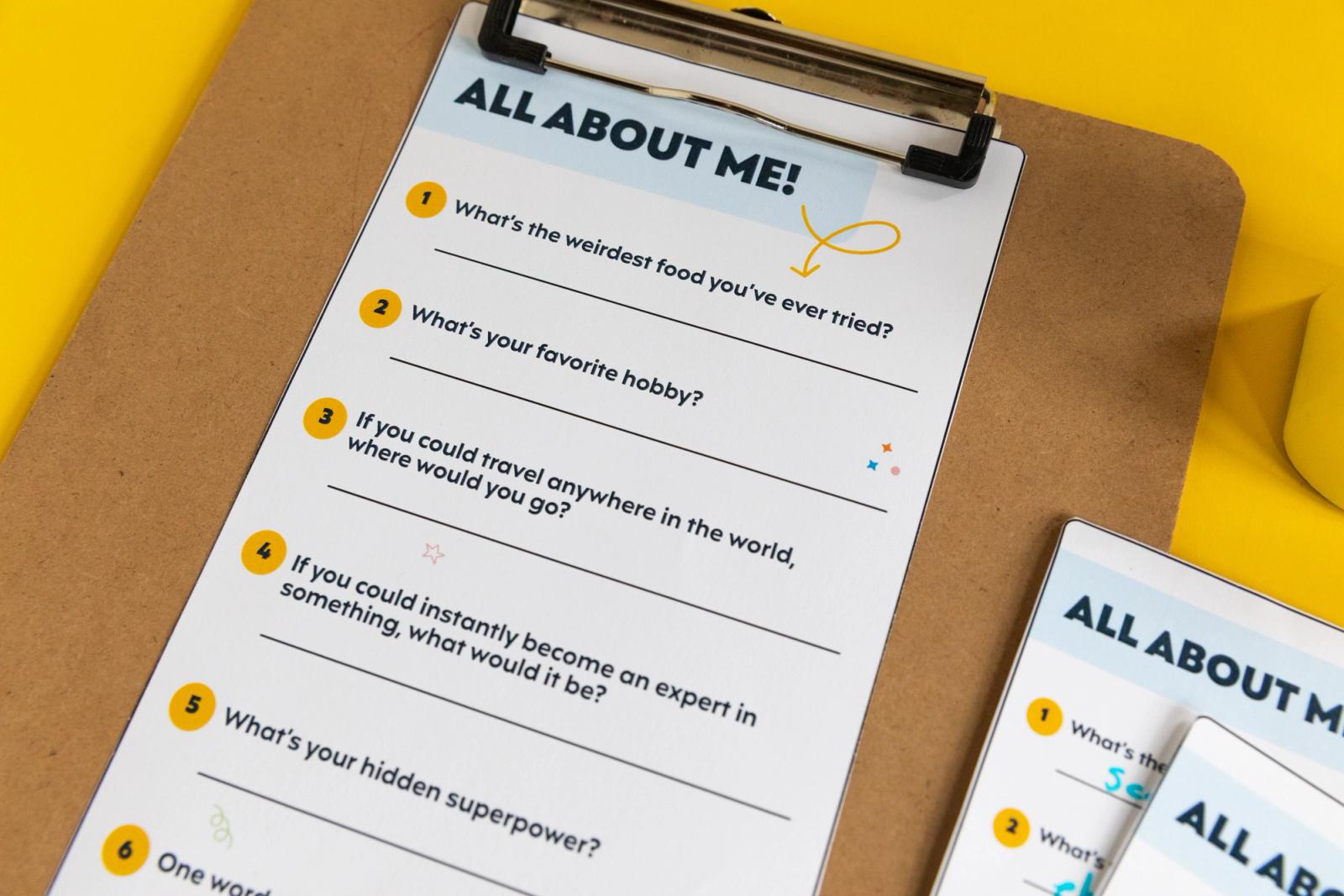 Closeup of a piece of paper that says "all about me" on a clipboard on a yellow background.