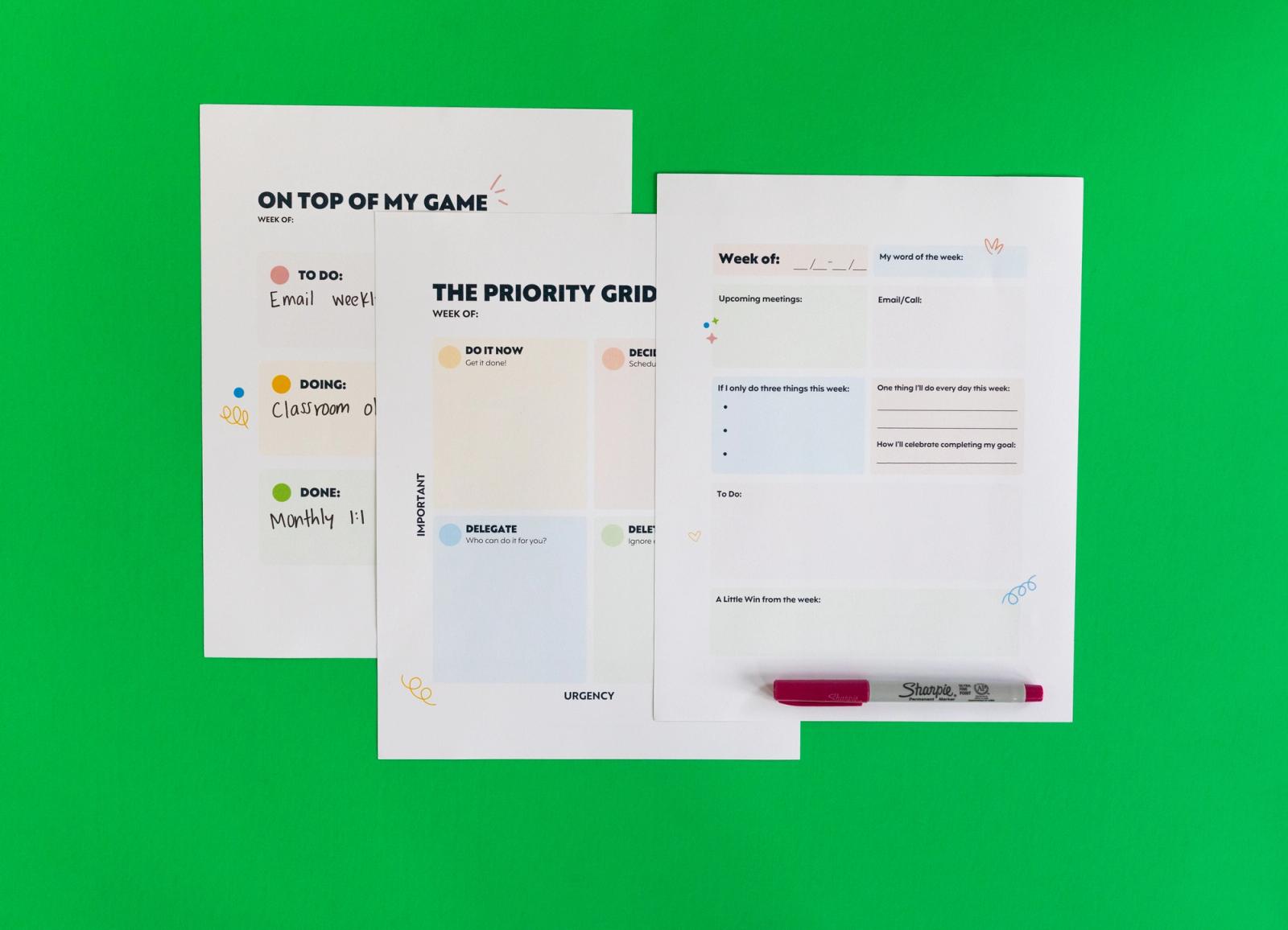 Three sheets of paper and a red pen lay on a green background.