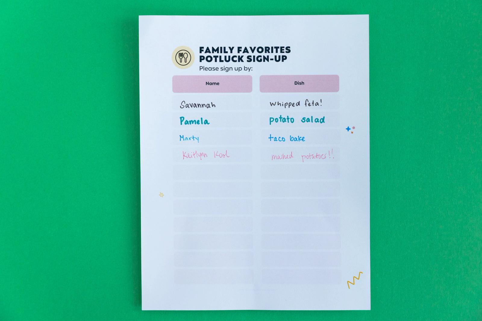 A sheet of paper that says "family favorites potluck sign-up" lays on a green background.