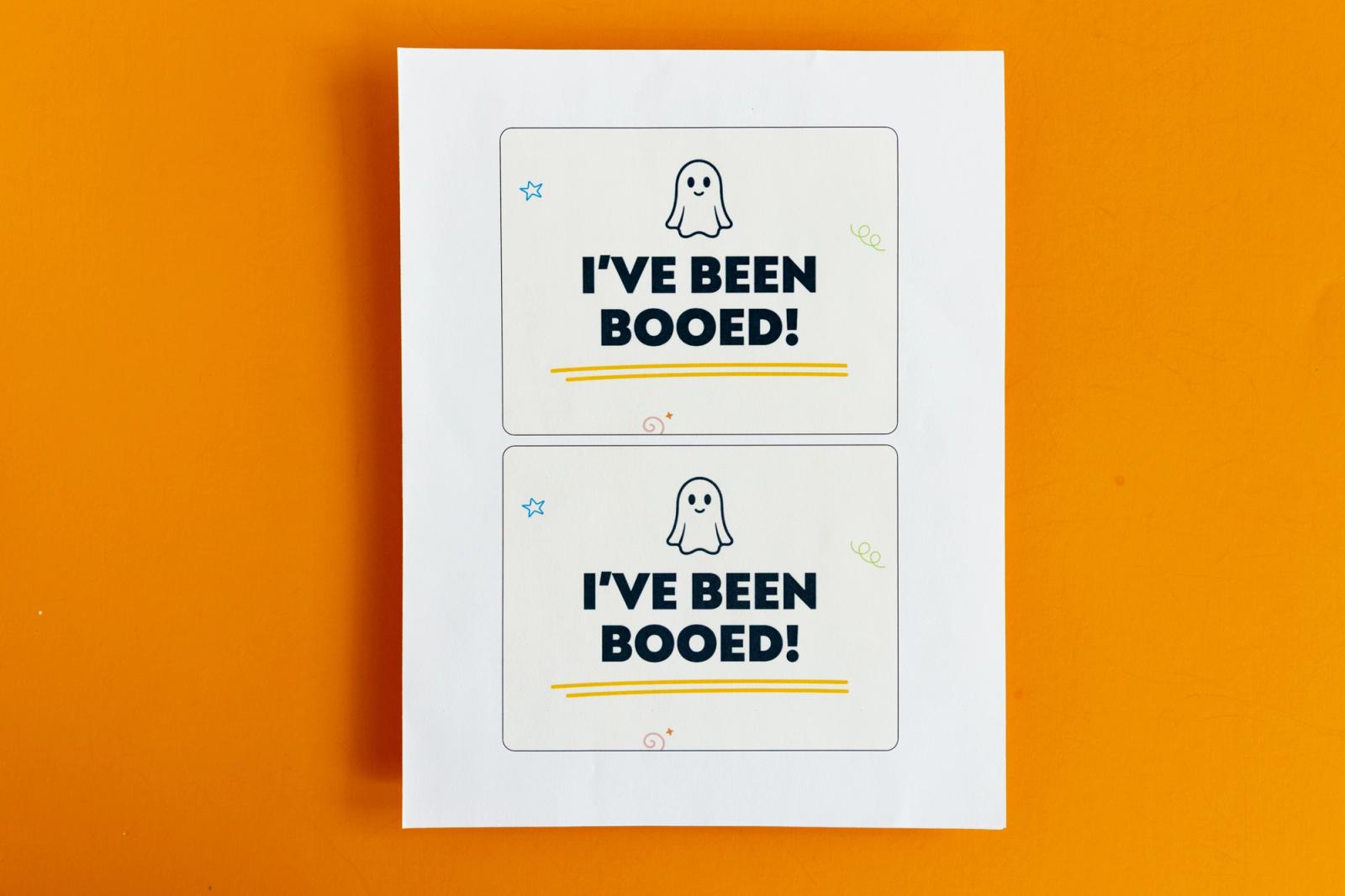 A piece of paper with two notecards that say "I've been booed" lays on an orange background.