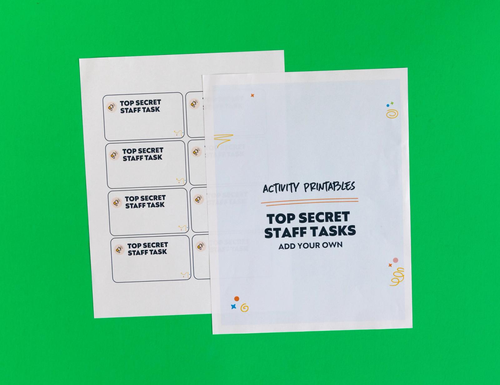 Two sheets of paper lay on a green background. One says "top secrete staff tasks: add your own." 