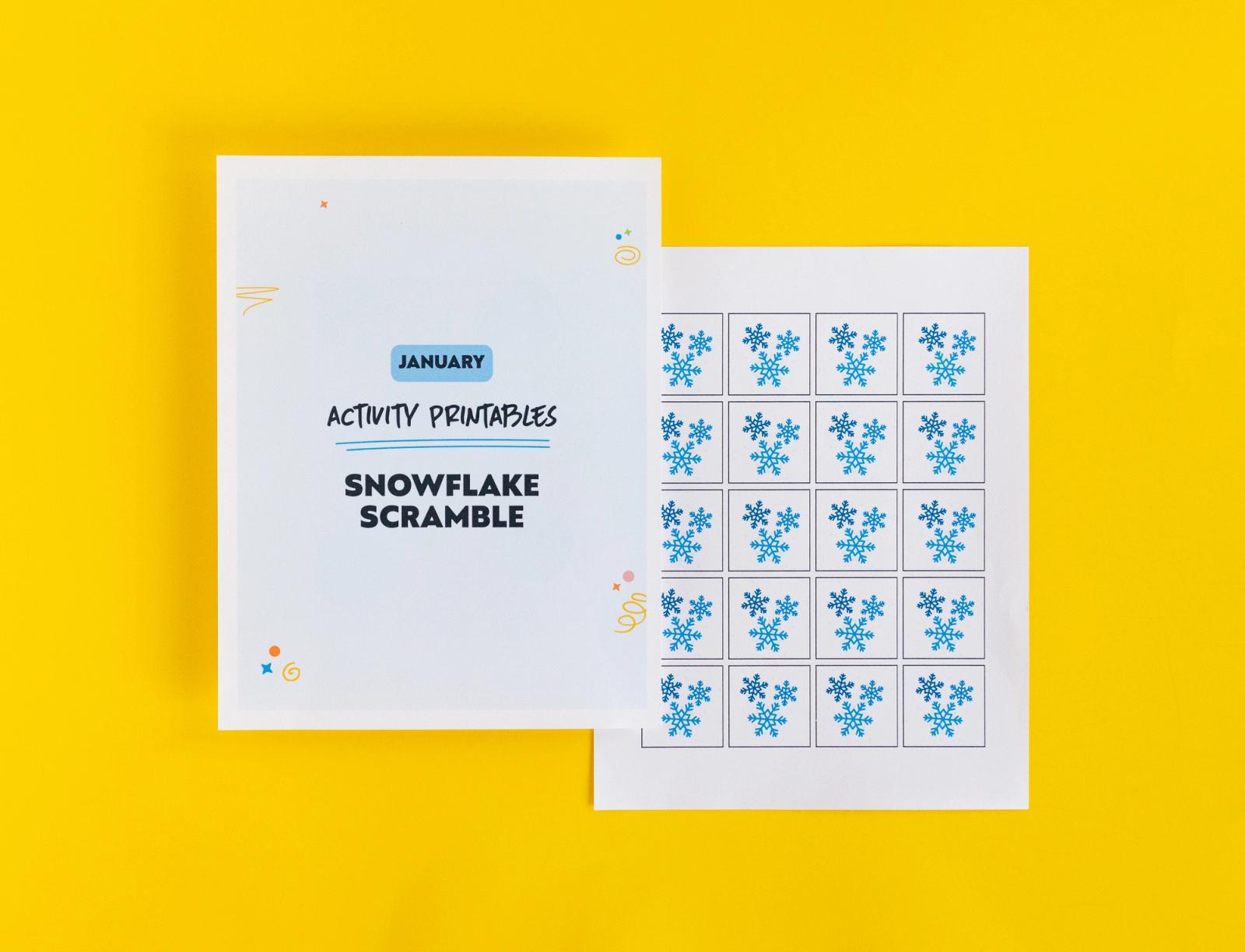 Paper that says "snowflake scramble" and paper with small pictures of blue snowflakes lay on a yellow background.