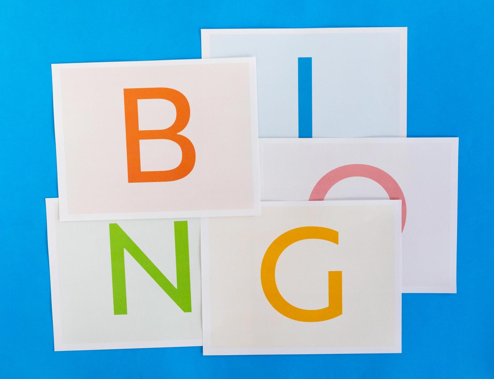 Sheets of paper each with a letter from "bingo" printed on them lay on a blue background.