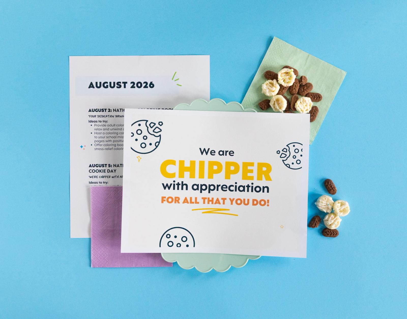 A poster that says "we are chipper with appreciation" lays on a plastic plate and napkins on a light blue background.