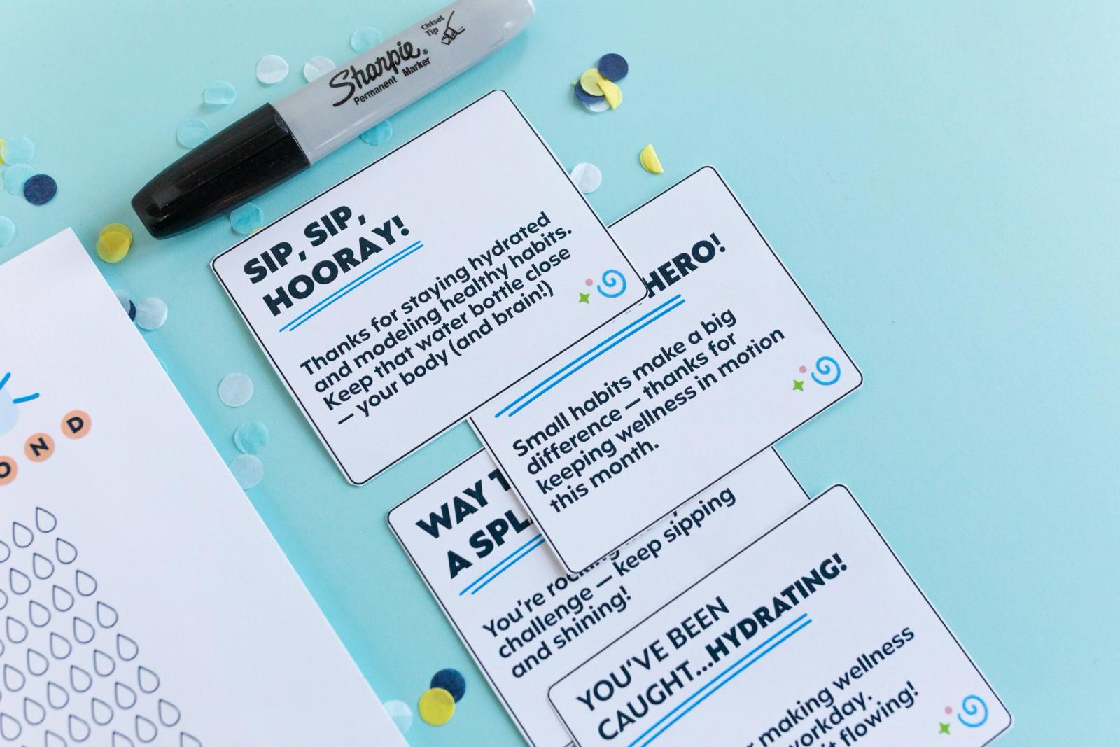 Closeup of small cards that say "sip, sip hooray" on them on a light blue background.
