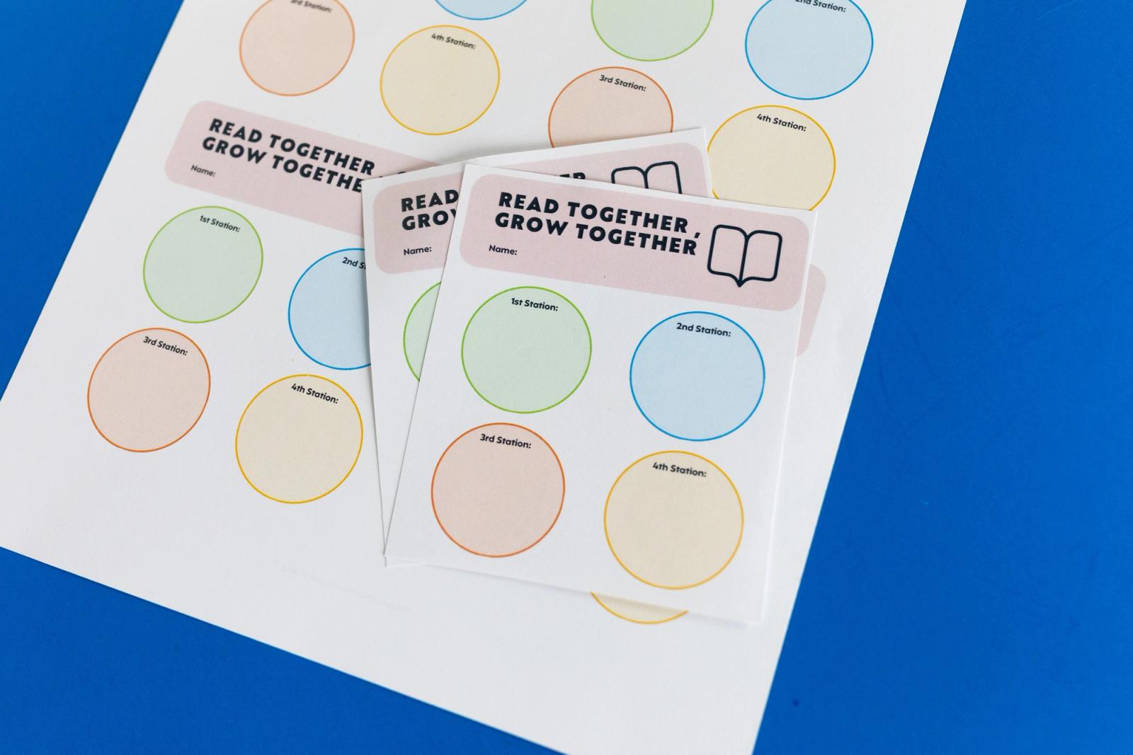 Sheets of paper with colorful circles on them and say "read together, growth together" lay on a blue background.