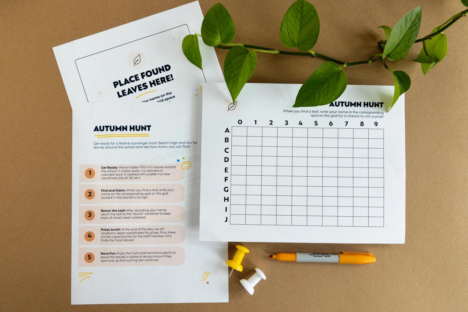 Three pieces of paper lay on a brown background. Leaves, push pins, and a marker lay around them.