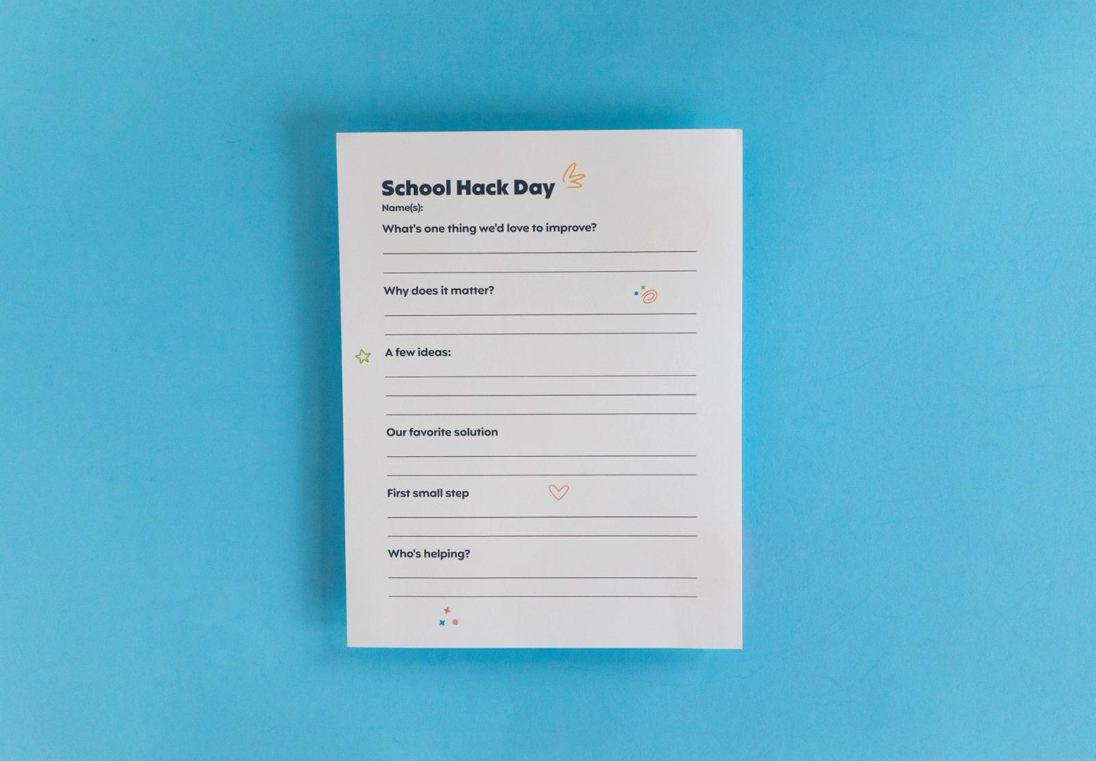Sheet of paper that says "school hack day" lays on a light blue background.