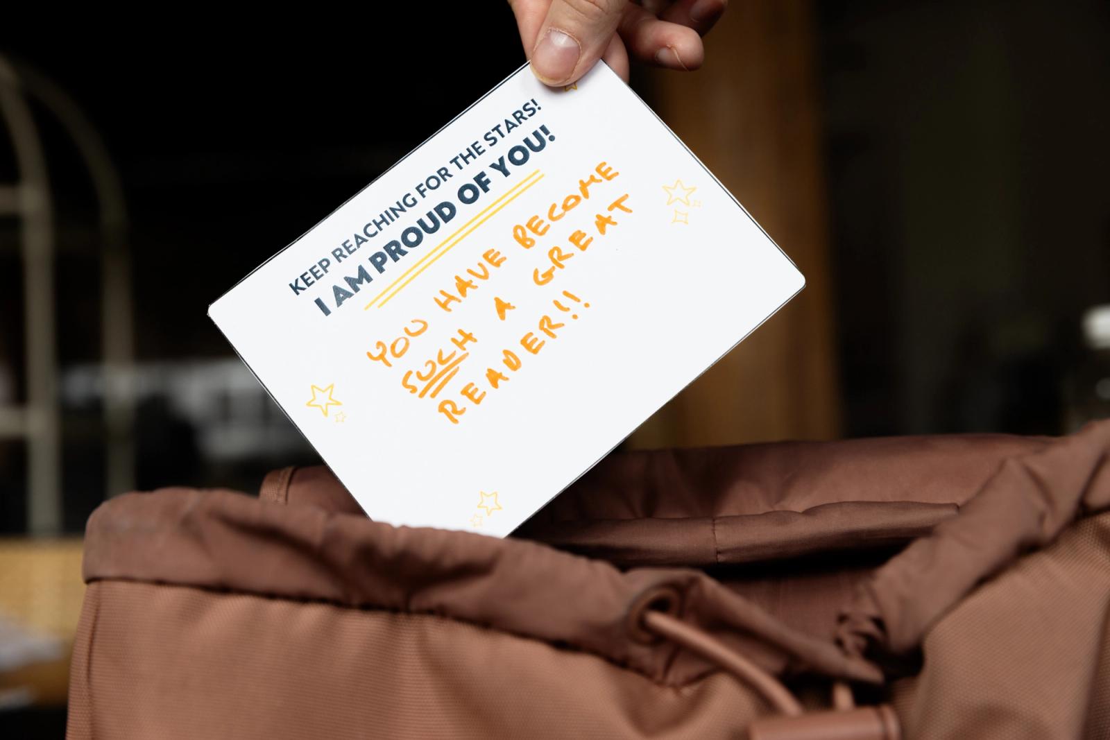 A hand places a handwritten note in a backpack.