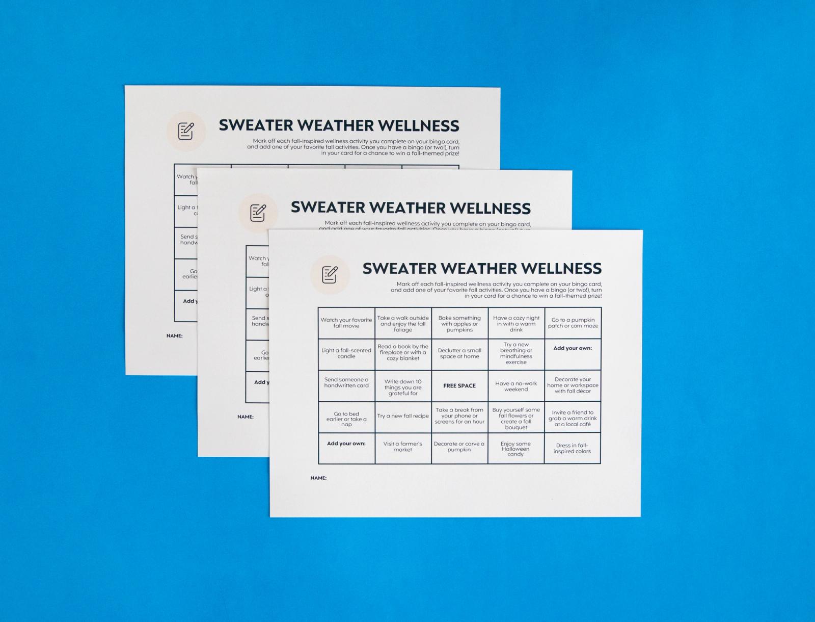 Three sheets of paper with bingo boards on them lay on a blue background.