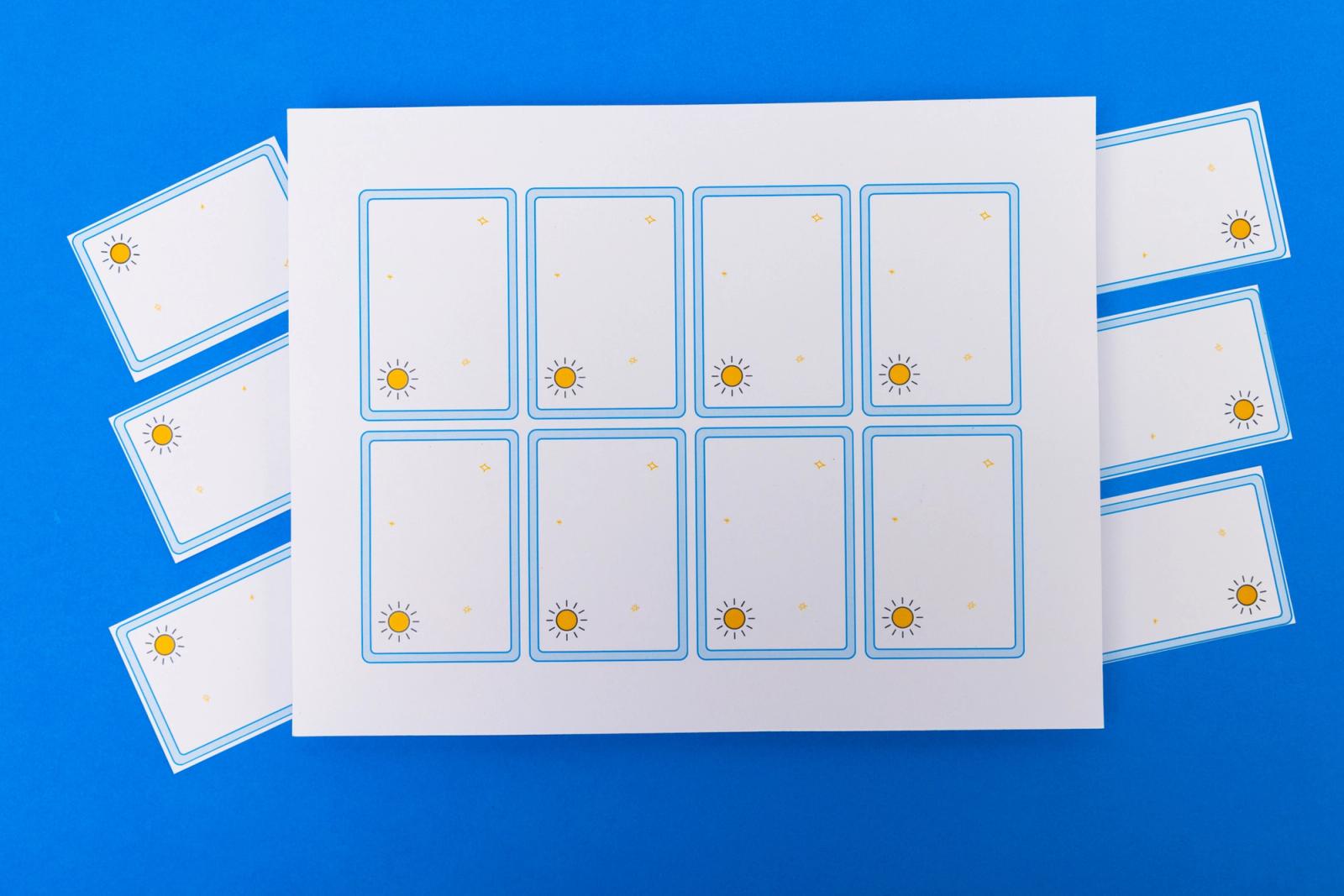 A sheet of paper with blank notecards on it lays on a blue background.