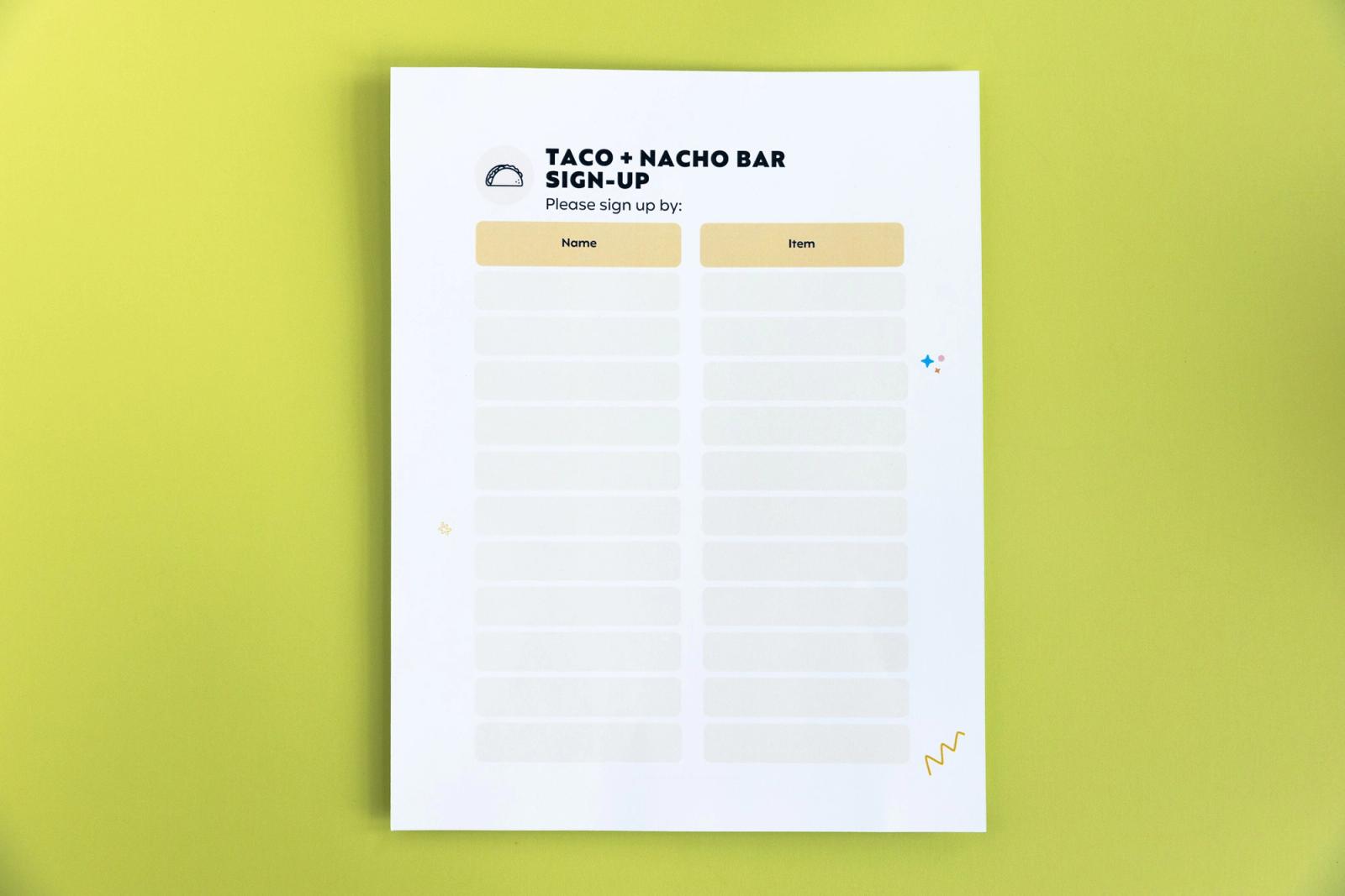 A paper that says "taco + nacho bar signup" lays on a light green background.
