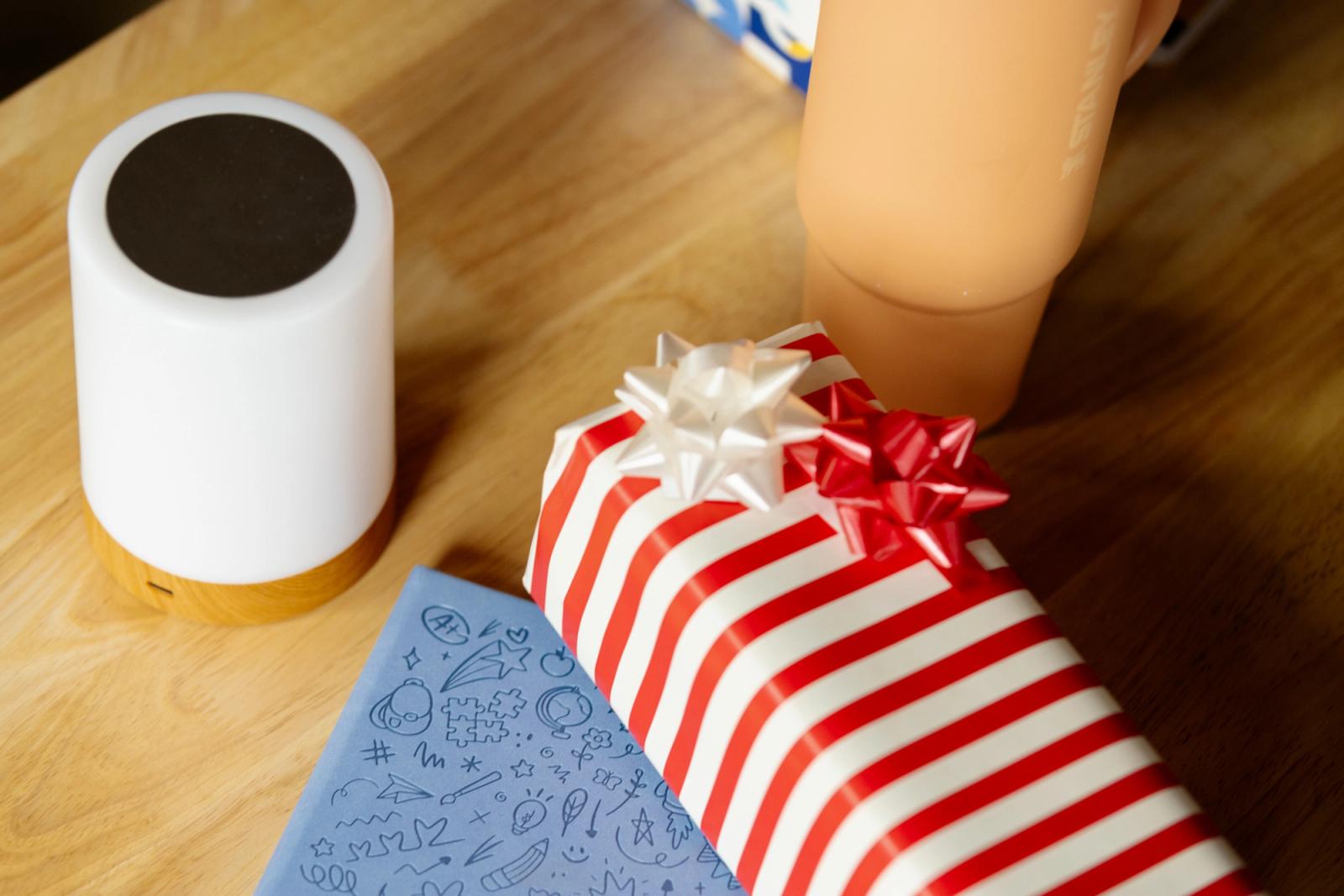 A holiday present wrapped in red and white paper lays on a desk.