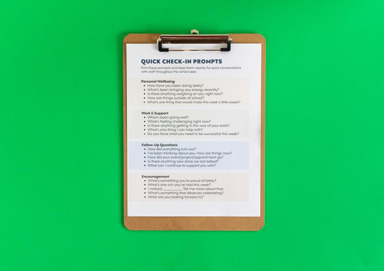 A sheet of paper that says "quick check-in prompts" is on a clipboard on a green background.