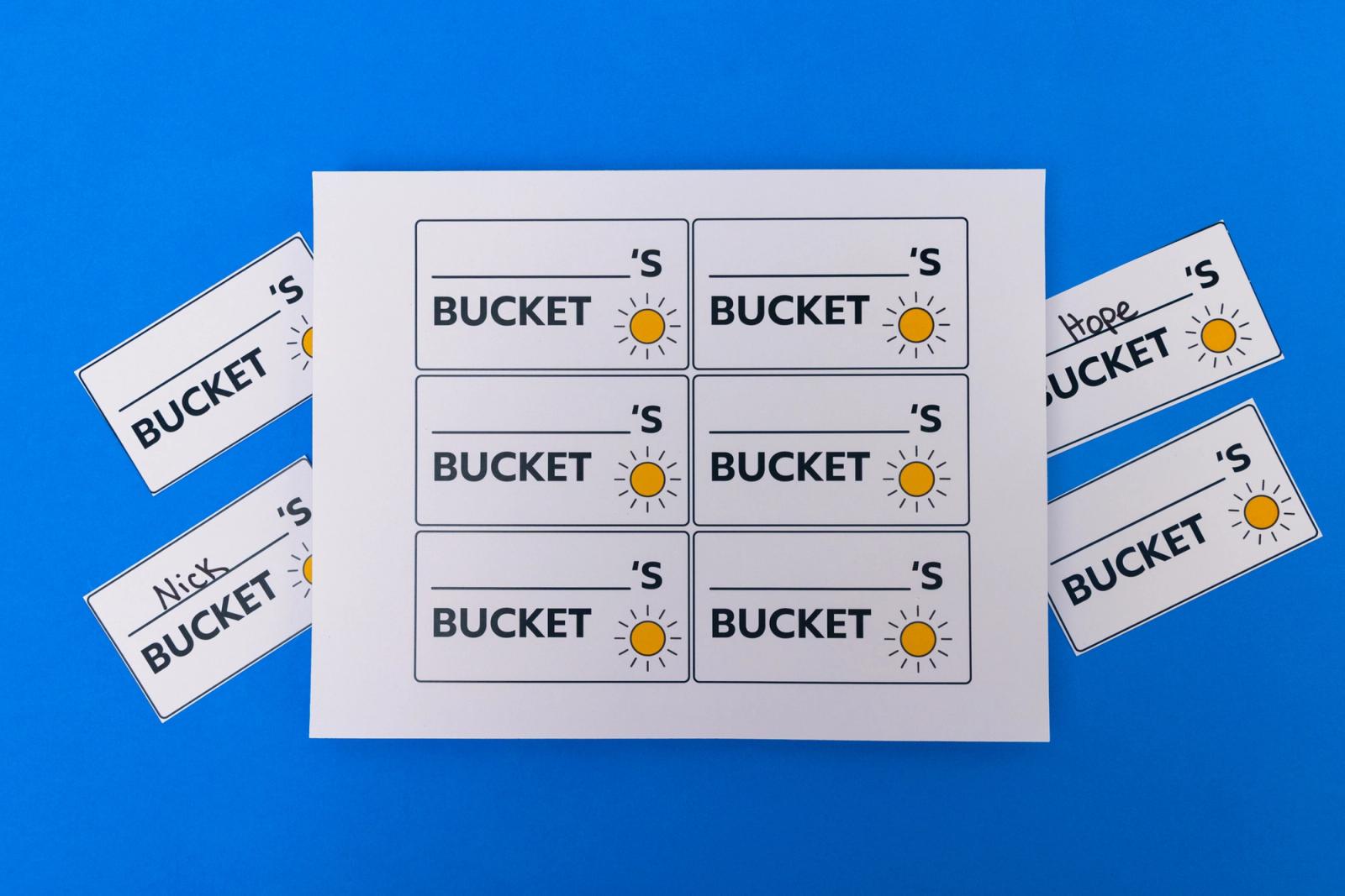 A sheet of paper that says "bucket" on it lays on a blue background.