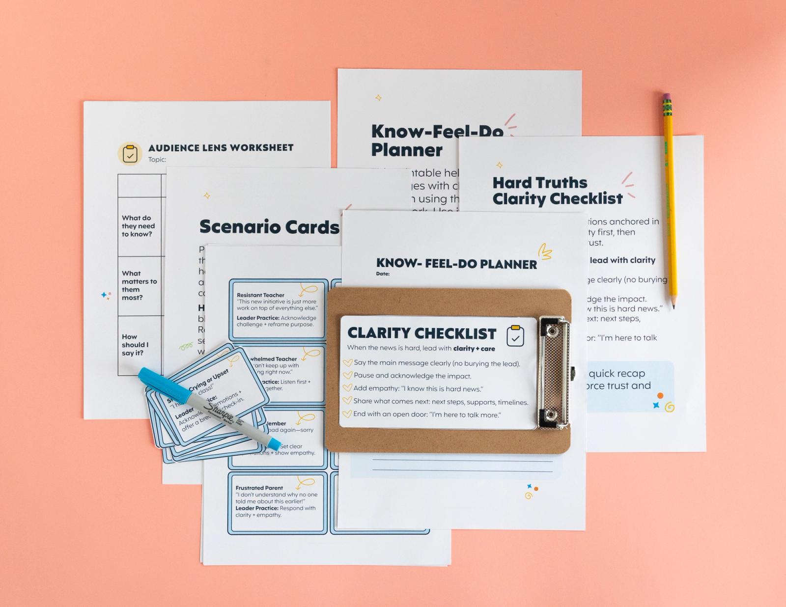 Several sheets of paper, a clipboard, notecards, a pencil, and pen lay on a light pink background.