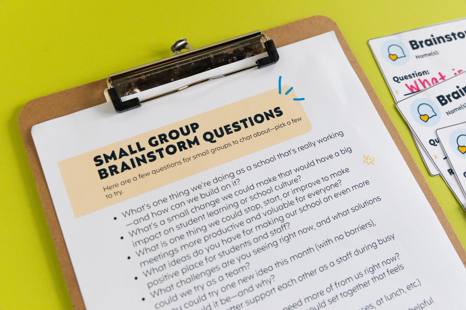 Closeup of a piece of paper that says "small group brainstorm questions" on a clipboard on a bright green background.