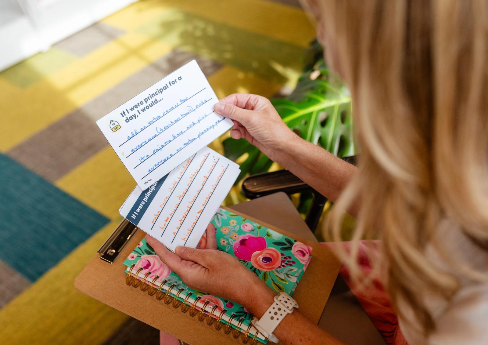 A woman sits reading notecards with hand-written notes on them. 