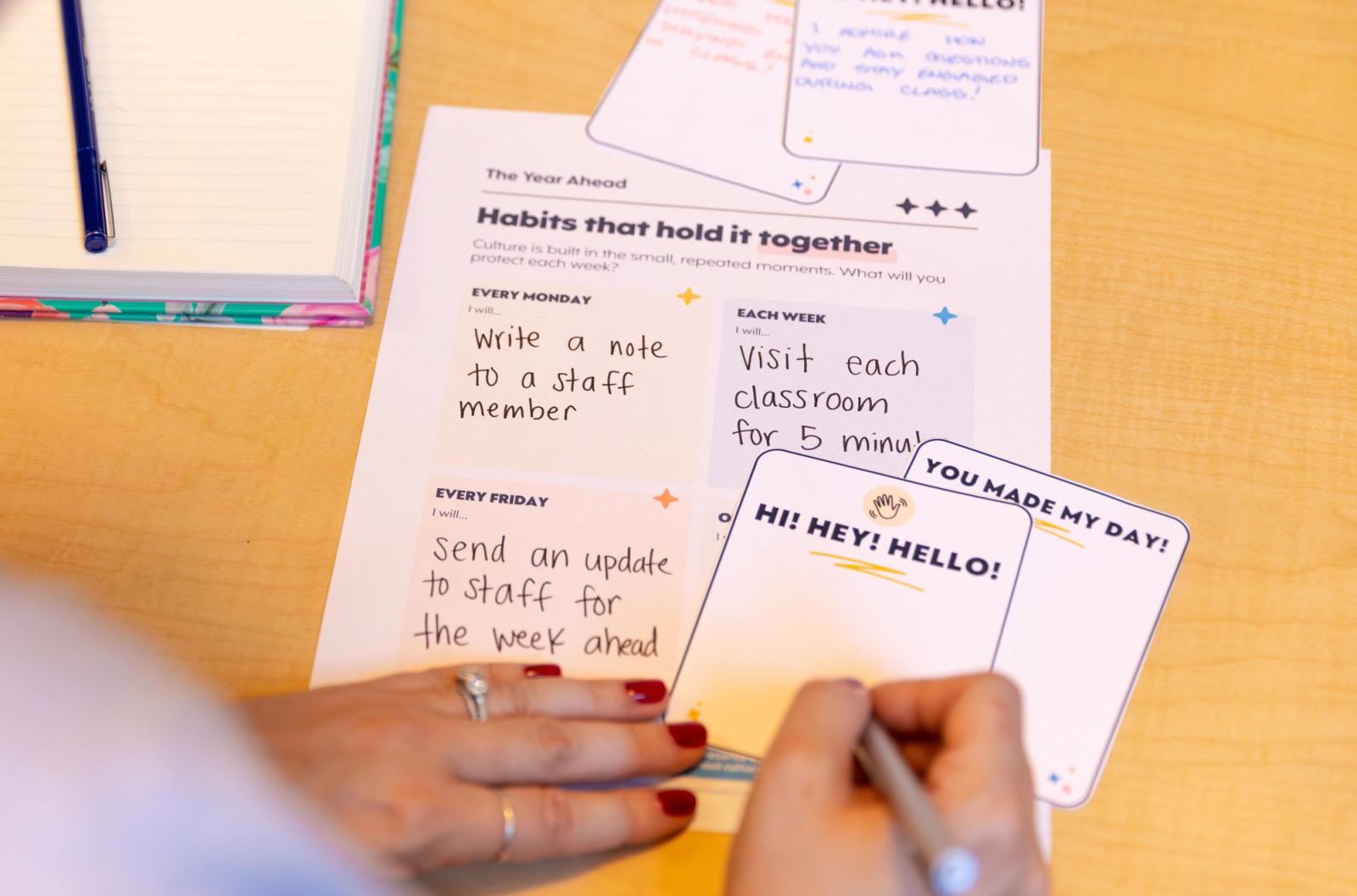 A person sitting at a table writes a hand-written note.