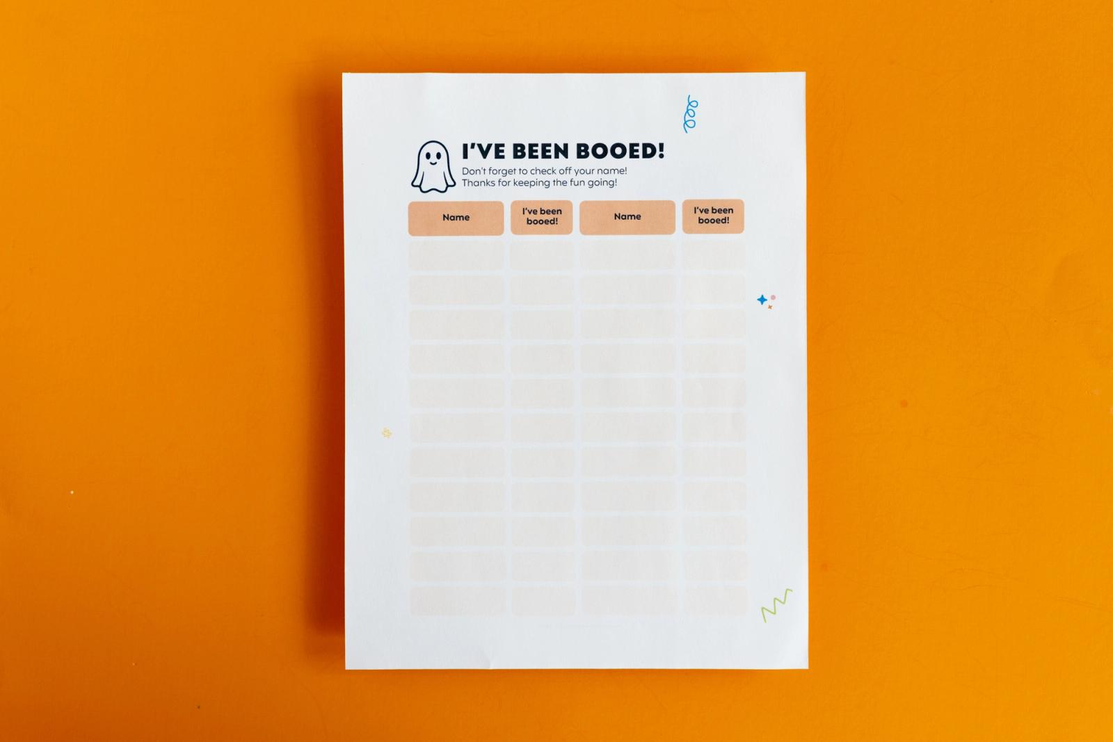 A piece of paper that says "I've been booed" lays on an orange background.