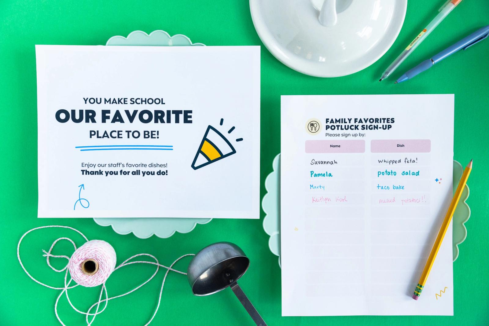 Two sheets of paper lay on a green background. Scattered around are pens and pencils, a ladle, and string.