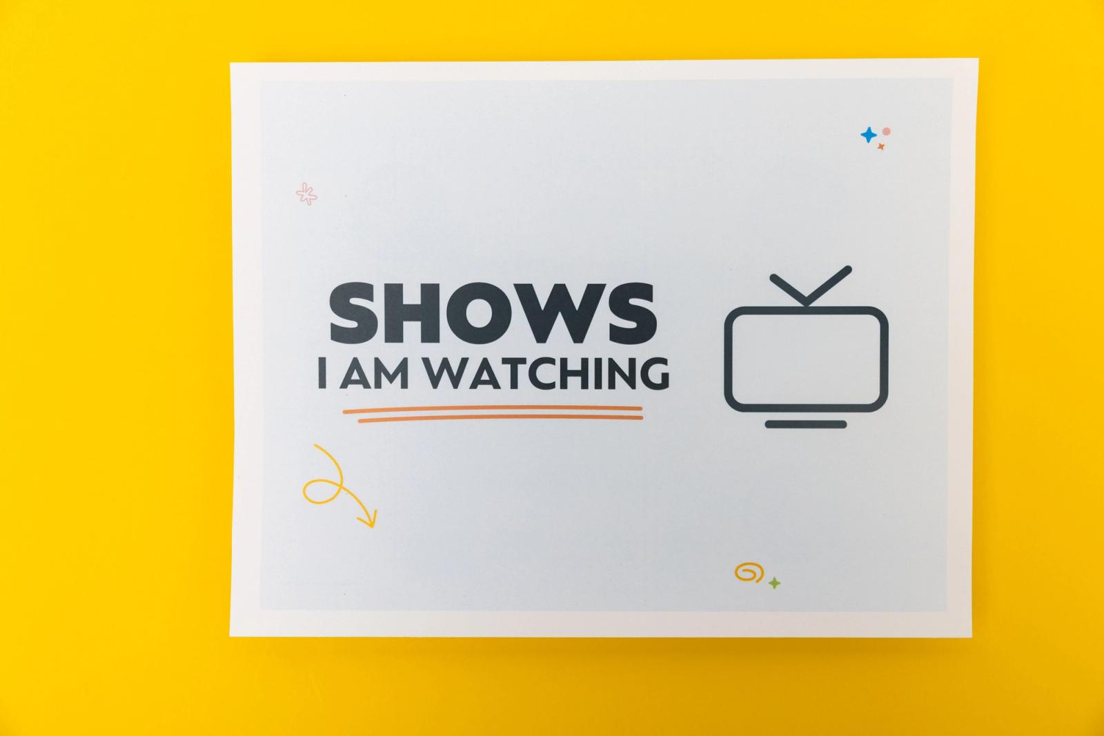 A piece of paper that says "shows I am watching" lays on a yellow background.