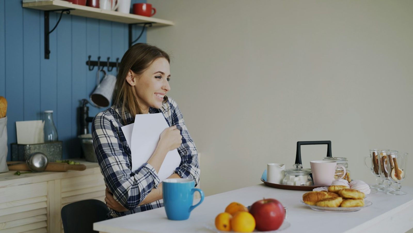 A person sitting at a kitchen table in the morning light, writing a short note in a notebook beside a cup of tea, photo by Vitaly Gariev on Unsplash