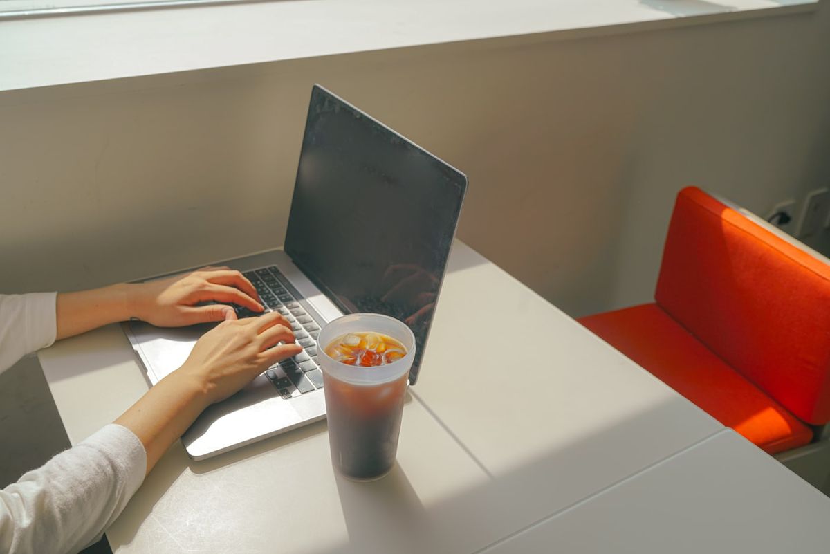 A simple bowl of beans, tuna and greens assembled on a desk beside a laptop and phone, photo by Trash Busters on Unsplash