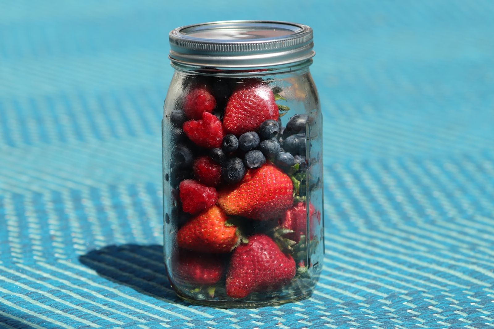 A glass jar of layered oats, yoghurt and berries sitting next to a bag, ready to take on the go, photo by Emma Johnson on Unsplash