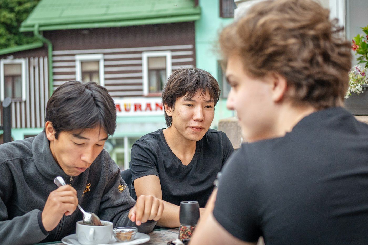 A small group of friends sharing plates of food and conversation at a casual restaurant table, photo by Timur Shakerzianov on Unsplash
