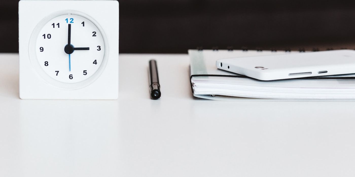 Clock on a desk with pen and notebook, representing the time cost of manual work
