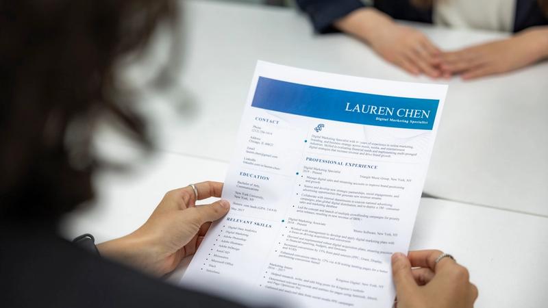 Hiring manager reading a printed resume at a table during a job interview